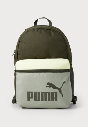 Mochila verde-oliva com um bolso frontal verde-claro, apresentando um grande logo PUMA cinza. Tecido suave, compartimentos com fecho éclair e bolso lateral em malha.