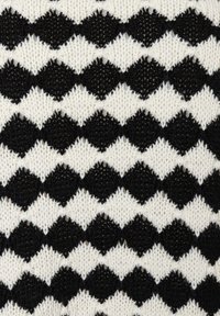 Black and white knit fabric featuring a diamond pattern with alternating solid and textured sections, creating a visually striking surface.