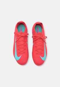 Czerwone korki piłkarskie Nike z turkusowymi akcentami, posiadające teksturowaną cholewkę, centralne sznurówki oraz wyraźny wzór logo Swoosh po obu stronach.
