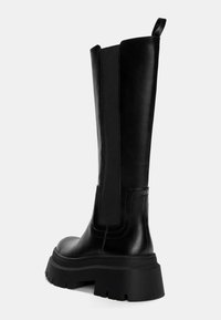 Schwarze Leder-Stiefel bis zum Knie mit einer robusten Sohle, elastischen Seitenteilen und einer Zuglasche an der Oberseite zum einfachen Anziehen. Glatte Textur, minimale Details.