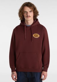 Bordeaux hoodie med en frontkangaroo-lomme og et broderet gult Vans-logo. Har en hætte med snøre og ribbede manchetter.