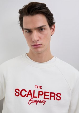 White sweatshirt with red embroidered text reading "THE SCALPERS Company." Features a round neck and raglan sleeves. Smooth texture.