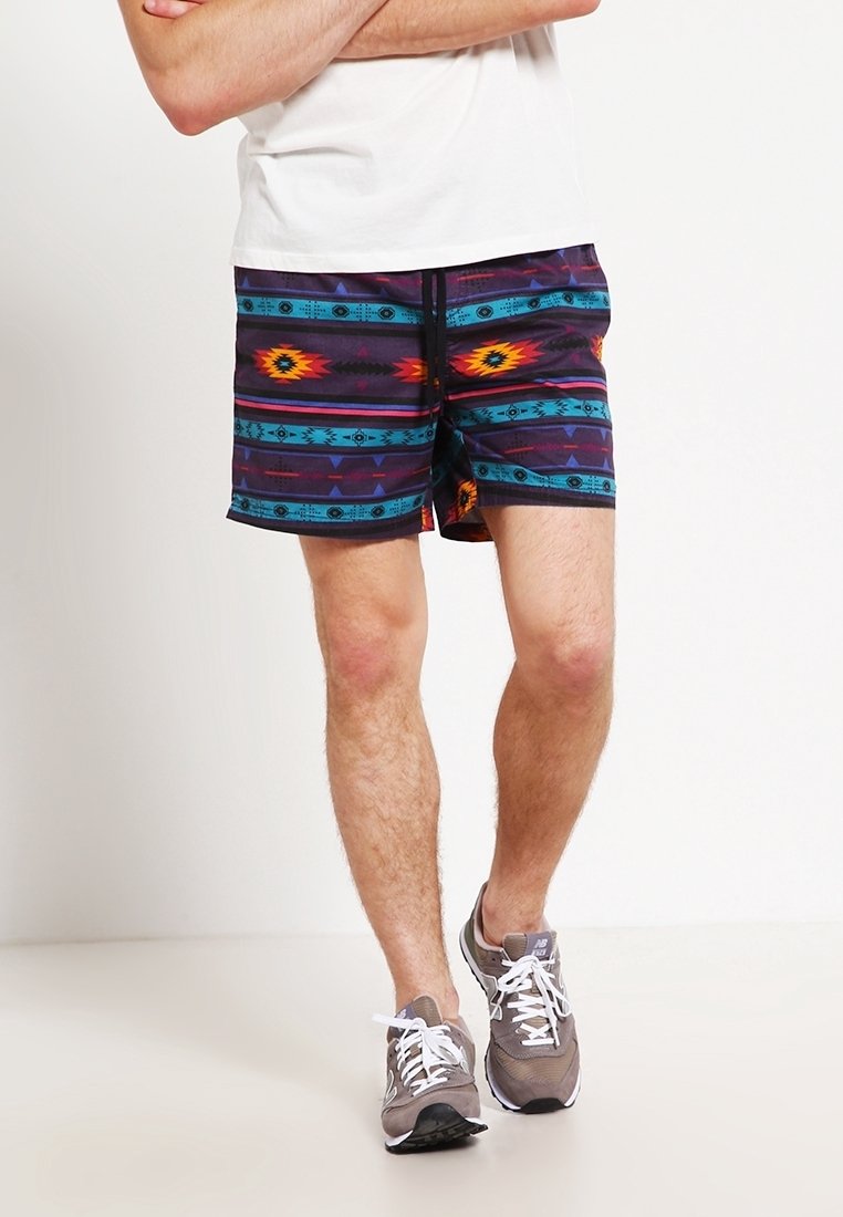 Bañador multicolor con un patrón tribal en tonos de morado, azul y naranja. Tejido ligero, cinturilla elástica, longitud por encima de la rodilla.