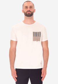 T-shirt bianco in cotone con maniche corte e una tasca rettangolare texture con tessuto a strisce multicolori sul lato sinistro.