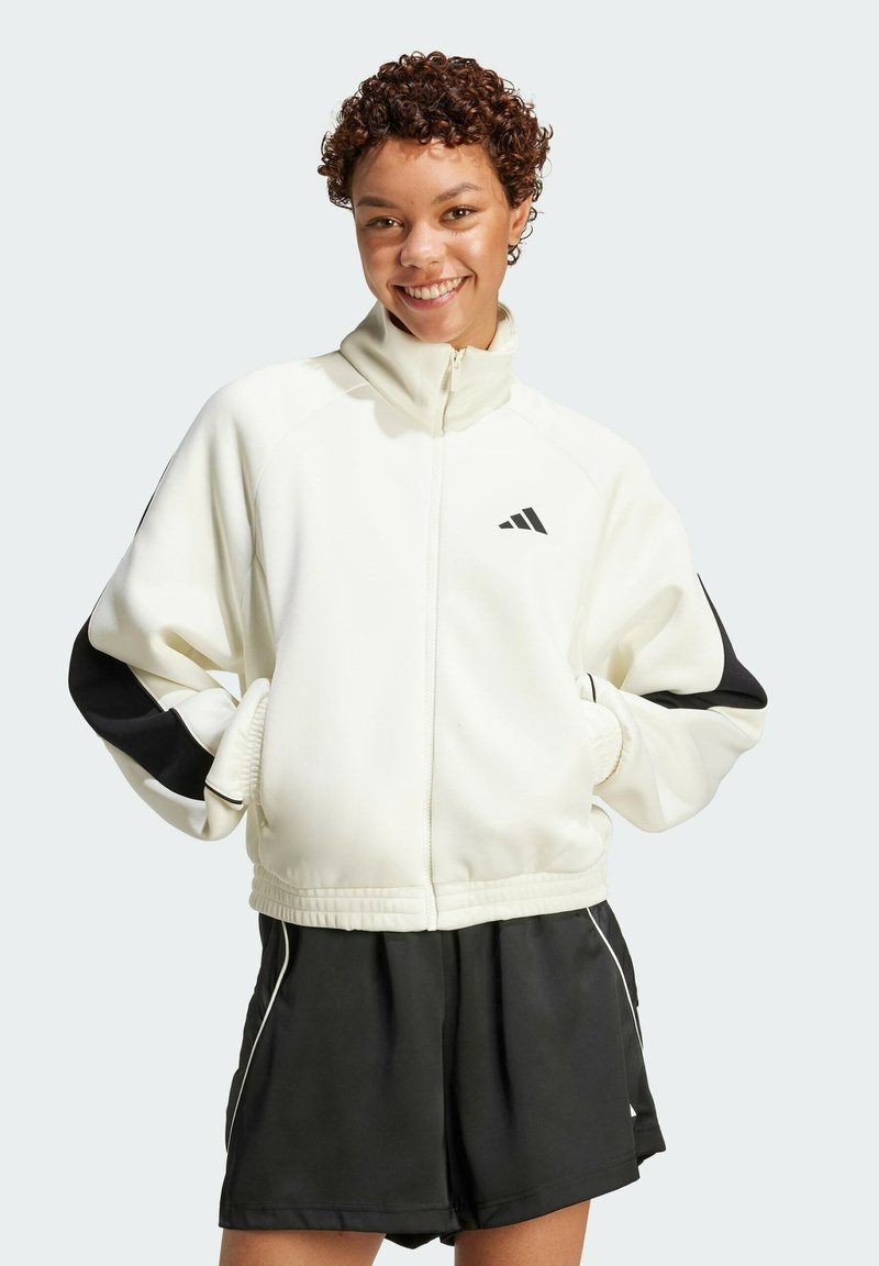 White sports jacket with black accents, zip closure, high collar, and elastic cuffs, paired with black shorts featuring white piping.