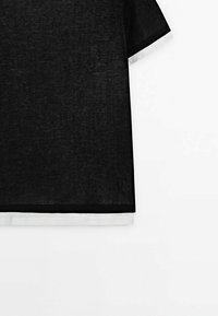 Black short-sleeve t-shirt with a textured fabric. Features white trim along the hem and sleeves. Simple, relaxed fit design.