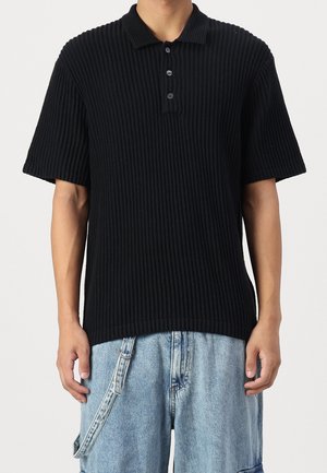 Schwarzes geripptes Poloshirt mit Kragen, kurzen Ärmeln und einer Knopfleiste mit drei Knöpfen. Das Material hat eine strukturierte Oberfläche.