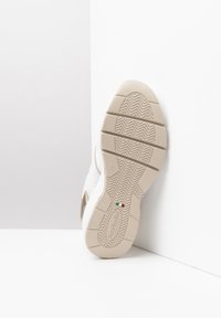 Shoe sole in beige rubber with textured grip pattern; features embossed logo detail on side and Italian flag accent. Flat, curved shape.