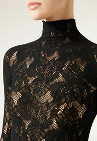 Haut col roulé en dentelle noire arborant des motifs floraux complexes, un design ajusté, un col haut et une texture transparente.