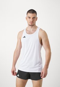 Hvid ærmeløs atletisk tanktop med rund halsudskæring, prydet med et sort logo på venstre bryst, parret med sorte shorts.
