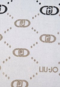 Textil de Liu Jo con un patrón de diamantes repetitivo en beige y marrón, con el nombre de la marca impreso en una fuente moderna sobre un fondo claro.