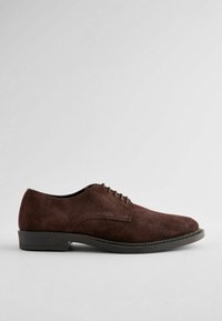 Zapatos de ante marrón con cordones, de textura suave, punta redonda y un bajo tacón de goma negra. Diseño sencillo con detalles de costura mínimos.