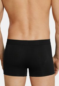 Zwarte katoenen boxershorts met een zachte textuur, elastische tailleband en korte benen, gezien van de achterkant, waarbij de pasvorm en het ontwerp worden benadrukt.