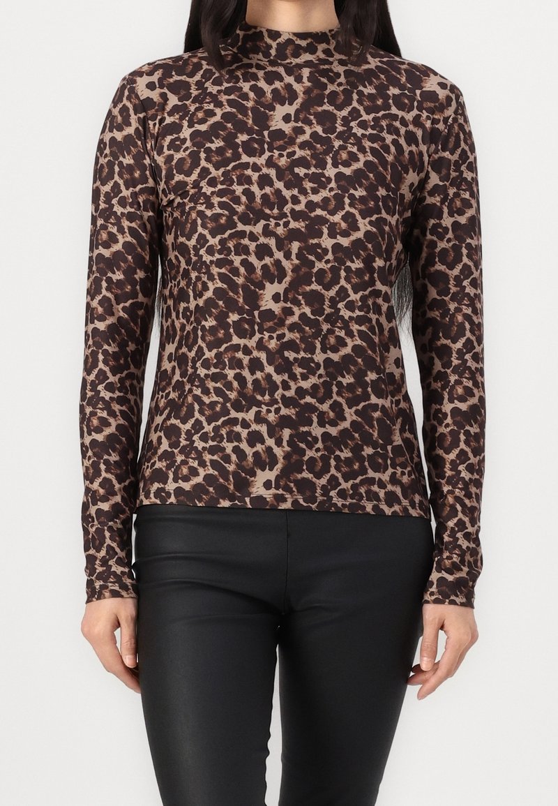 Langarmoberteil im Leopardenmuster mit hohem Kragen. Der Stoff ist glatt und hat ein braun-beiges Farbschema. Kombiniert mit schwarzen Leggings.
