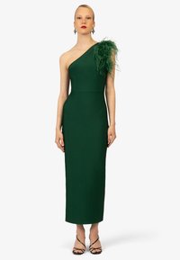 Groene, getailleerde, een-schouder jurk met een veeraccent op de linkerschouder. Knie-lange, elegante ontwerp, gemaakt van glad materiaal, minimale versieringen.