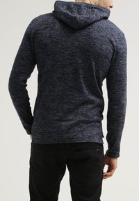 Mörkblå hoodie med en melerad textur, långa ärmar och en avslappnad passform. Har en huva och diskret detaljer vid halsringningen.