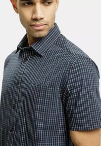 Koszula z krótkim rękawem zapinana na guziki w granatowym kolorze w kratę. Posiada kołnierzyk, kieszeń oraz gładką bawełnianą strukturę. Dopasowany krój.