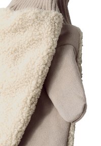 Puchaty, biały shearling i gładki, beżowy materiał łączą się w podzielonym wzorze, z teksturowanym, dzianinowym mankietem dla dodatkowego komfortu.