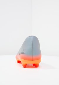 Šedý fotbalový kopačka s oranžovým gradientním s podešví. Disponuje hladkým syntetickým materiálem, minimálním brandingem a texturovaným povrchem pro lepší grip.