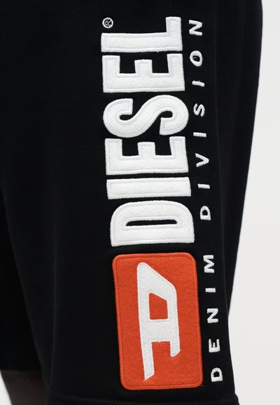 Tissu de sweat-shirt noir avec un grand texte brodé en blanc "DIESEL" et un patch orange avec une lettre blanche "A" et "DENIM DIVISION."