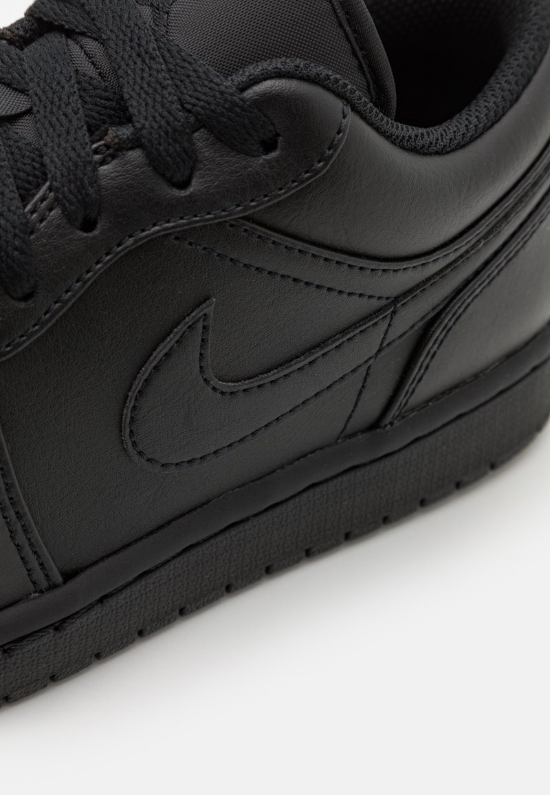 Czarne sneakersy Nike z gładką, skórzaną cholewką, fakturowanym obszarem sznurowania i wzorzystą gumową podeszwą; mają wytłoczone logo po boku.
