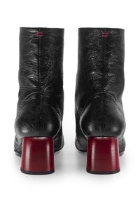 Stivaletti neri in pelle con una finitura testurizzata e un audace tacco rosso a blocco, con due piccoli dettagli rossi vicino alla parte superiore.