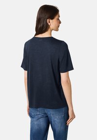 Camiseta de manga corta azul marino hecha de un textil suave, que presenta un corte holgado y un cuello redondo. Diseño liso en la parte posterior sin adornos.