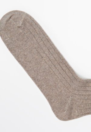 Brun ribbet sok med en blød tekstur, der har forstærkede tå- og hælområder, der viser et klassisk design og en glat overflade.