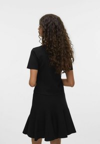 Robe en tricot noir avec un corsage ajusté et une jupe évasée. Manches courtes, texture lisse et ourlet au genou.