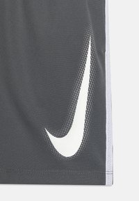 Pantalones cortos deportivos grises hechos de una tela transpirable, con el logo de Nike en blanco y acentos punteados en las costuras laterales.