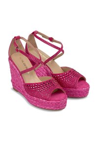 Sandalias de cuña rosa con base de paja trenzada, adornadas con rhinestones en la parte superior, con tiras cruzadas en el tobillo y punta abierta.