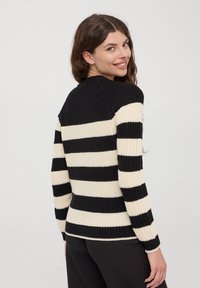 Czarny i kremowy sweter w paski, dziany, z prążkowaną teksturą, okrągłym dekoltem i długimi rękawami. Posiada poziome paski i luźny krój.