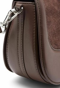 Bruine leren handtas met suede accenten, voorzien van een afgeronde vorm, gestikte details en een metalen clip voor het bevestigen van de strap.