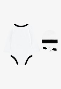 Vit långärmad bodies med svart kant, tillsammans med en matchande svart och vit mössa och sockar. Bomullsmaterial, mjuk textur.