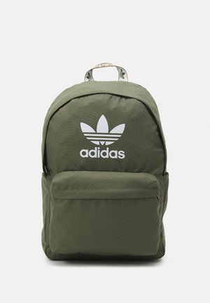 Zaino in tessuto verde con parte superiore arrotondata, logo adidas bianco, tasca frontale e maniglia di trasporto. Superficie testurizzata e dettagli di cucitura visibili.