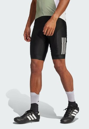 Black athletic shorts made of smooth fabric with white stripes on the left side, paired with black cycling shoes and gray high socks.