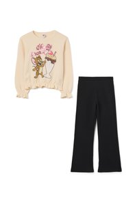 Camisa de manga larga beige con un gráfico de dibujos animados de un ratón y un helado sundae; combinada con pantalones de campana negros, con cintura elástica.