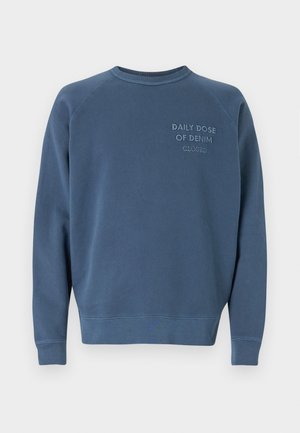 Sweatshirt azul de gola redonda feito de um tecido misto de algodão. Apresenta punhos e bainha canelados, com texto bordado no peito. Design simples.