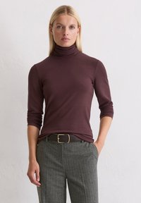 Bordowy sweter z kołnierzem, z długimi rękawami, dopasowany krój, gładka textura. W połączeniu z szarymi spodniami w paski i brązowym paskiem z złotą klamrą.