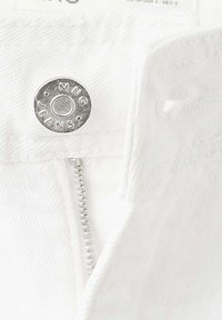 Gros plan sur un jean en denim blanc avec un bouton argenté portant l’inscription MNG JEANS et une fermeture éclair partiellement visible.