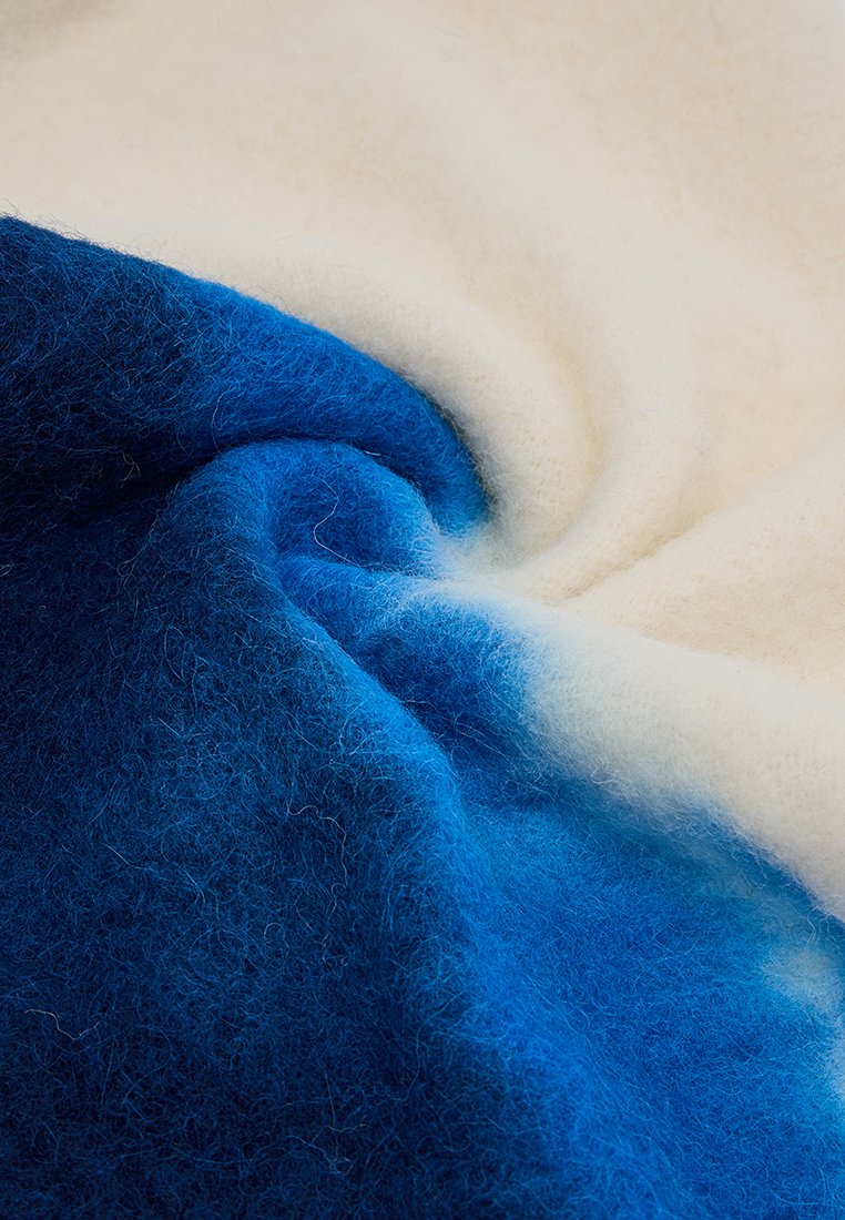 Wollen stof in blauw- en crèmekleuren, met een zachte, fuzzy textuur en een gradient effect van donkerblauw naar licht crème.