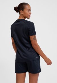 Czarna sportowa koszulka z krótkimi rękawami, okrągłym dekoltem i płaskimi szwami, w zestawie z dopasowanymi czarnymi szortami. Gładki materiał, minimalne oznakowanie.