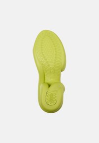 Green rubber shoe sole with textured patterns, including an oval and floral design, featuring a raised heel and smooth edges.
