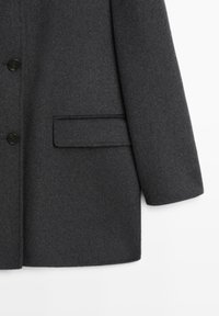 Cappotto di lana grigio scuro con una vestibilità strutturata, dotato di chiusura a bottone, una tasca sul petto e texture liscia.