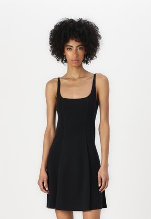 Vestido negro de canalé con escote cuadrado, tirantes finos, cuerpo ajustado y falda acampanada. Textura suave con color sólido, sin patrones.