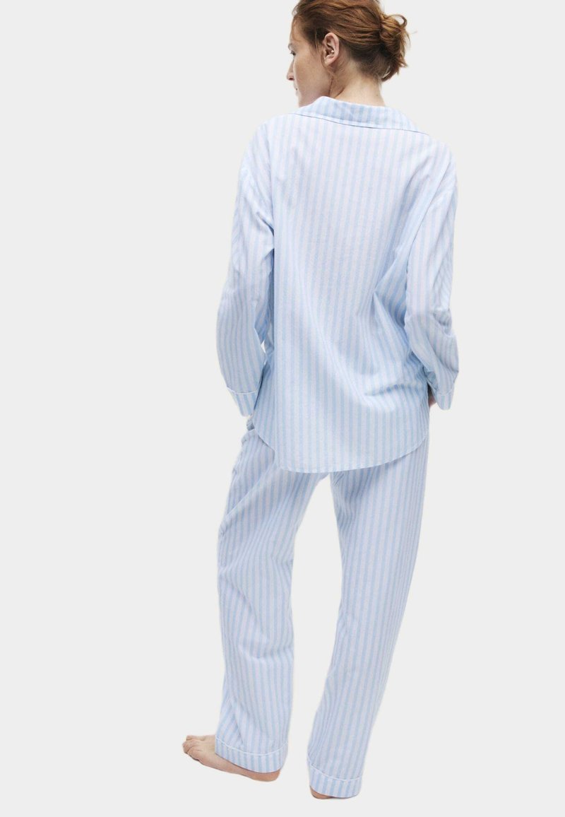 Lichtblauw en wit gestreept pyjamapakket, met een lange mouwen knoopsluiting top en loszittende broeken. Katoenen materiaal met een zachte textuur.