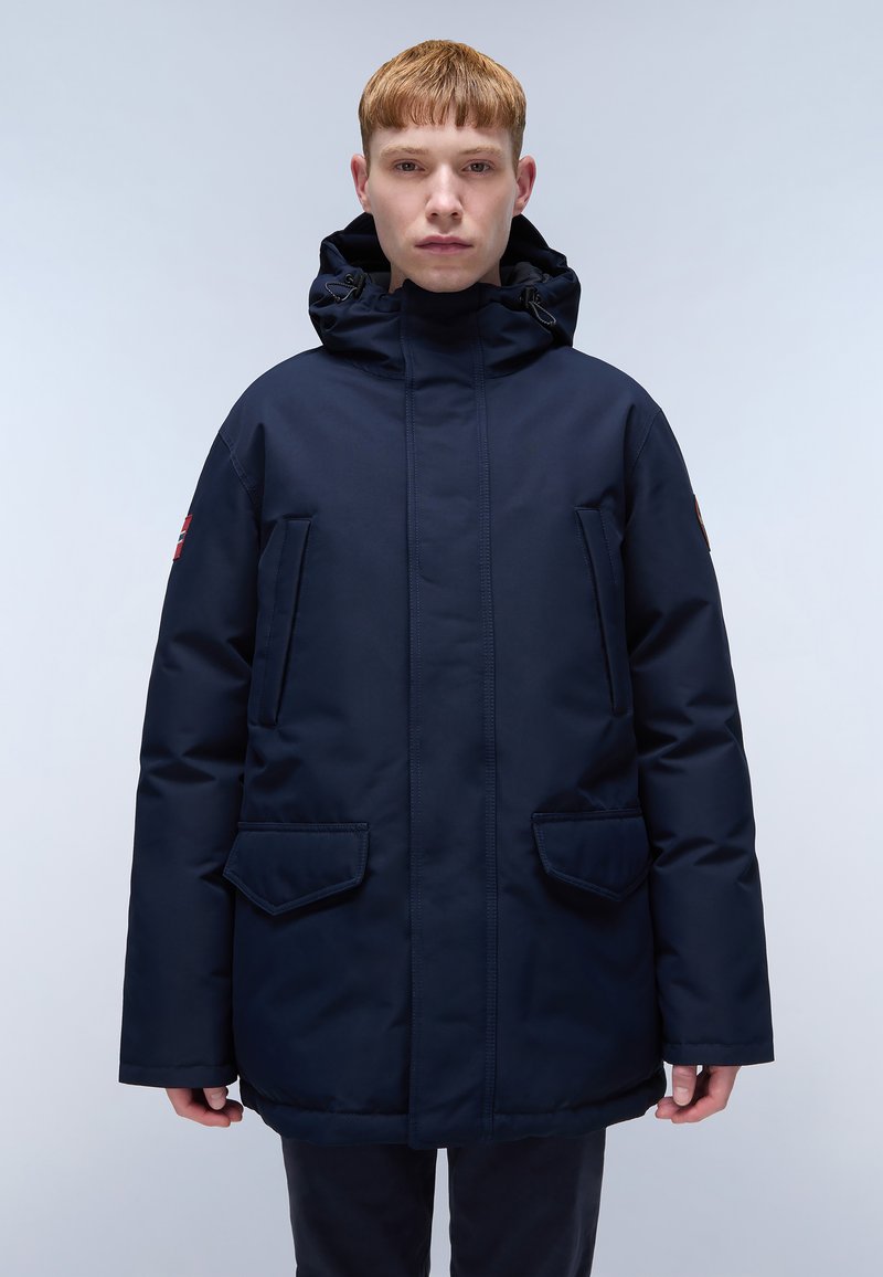 Parka isolata di colore blu navy con colletto alto e cappuccio regolabile, dotata di due tasche anteriori a toppa e di un logo sulla manica.