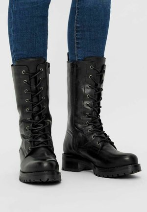 Zwarte leren militaire laarzen met veters aan de voorkant, zijrits en robuuste zool. Voorzien van een afgeronde neus en een gestructureerde afwerking.