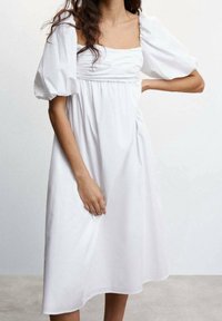 Weißes Kleid mit quadratischem Ausschnitt und puffierten kurzen Ärmeln. Hergestellt aus leichtem Stoff, mit einer lockeren Passform und dezentem Gather am Bund.