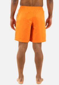 Pantaloni da bagno arancioni con vita elastica, lunghezza sopra il ginocchio e texture liscia. Nessun motivo visibile o dettagli hardware.